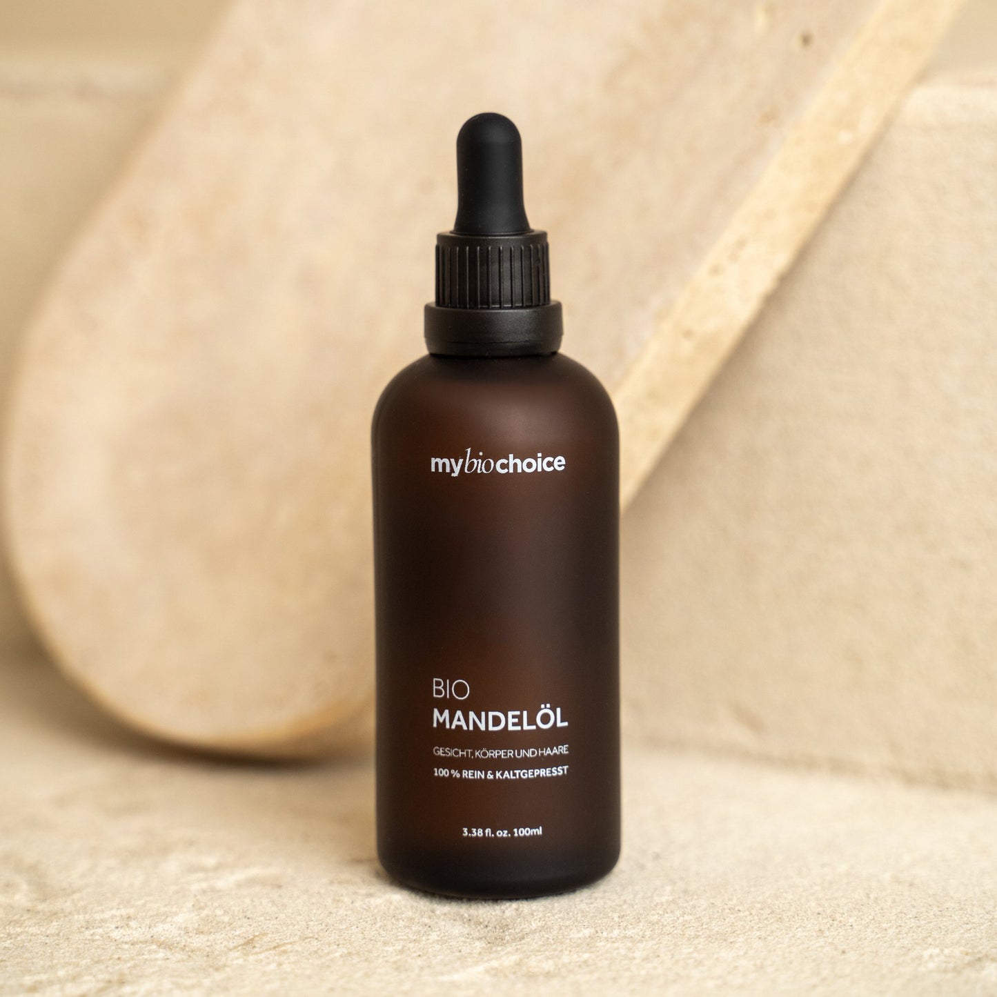 Bio olej migdałowy mybiochoice 100 ml ustawiony na jasnej kamiennej powierzchni w minimalistycznym stylu.