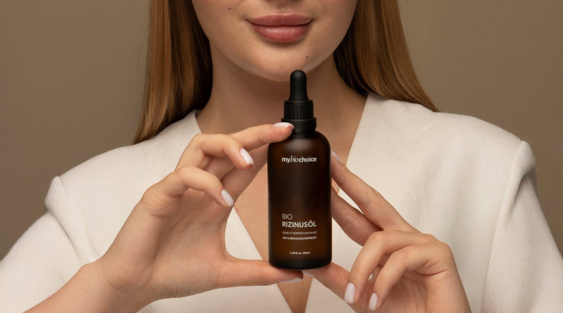 Bio Rizinusöl von mybiochoice, umgeben von Naturmaterialien – Baumrinde und gelben Blüten, symbolisieren die organische Qualität des Produkts.
