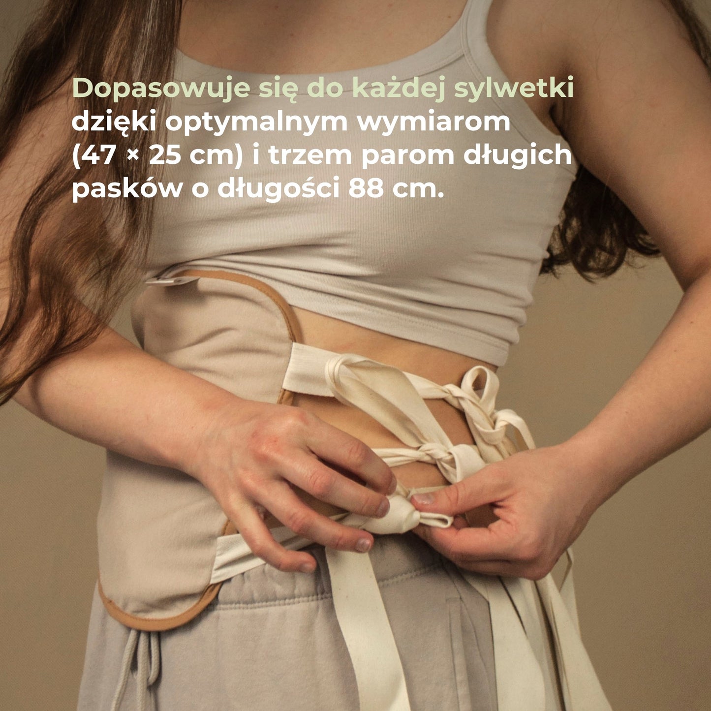Kobieta wiąże opaskę do okładów z oleju rycynowego, dopasowaną do sylwetki dzięki długim paskom.