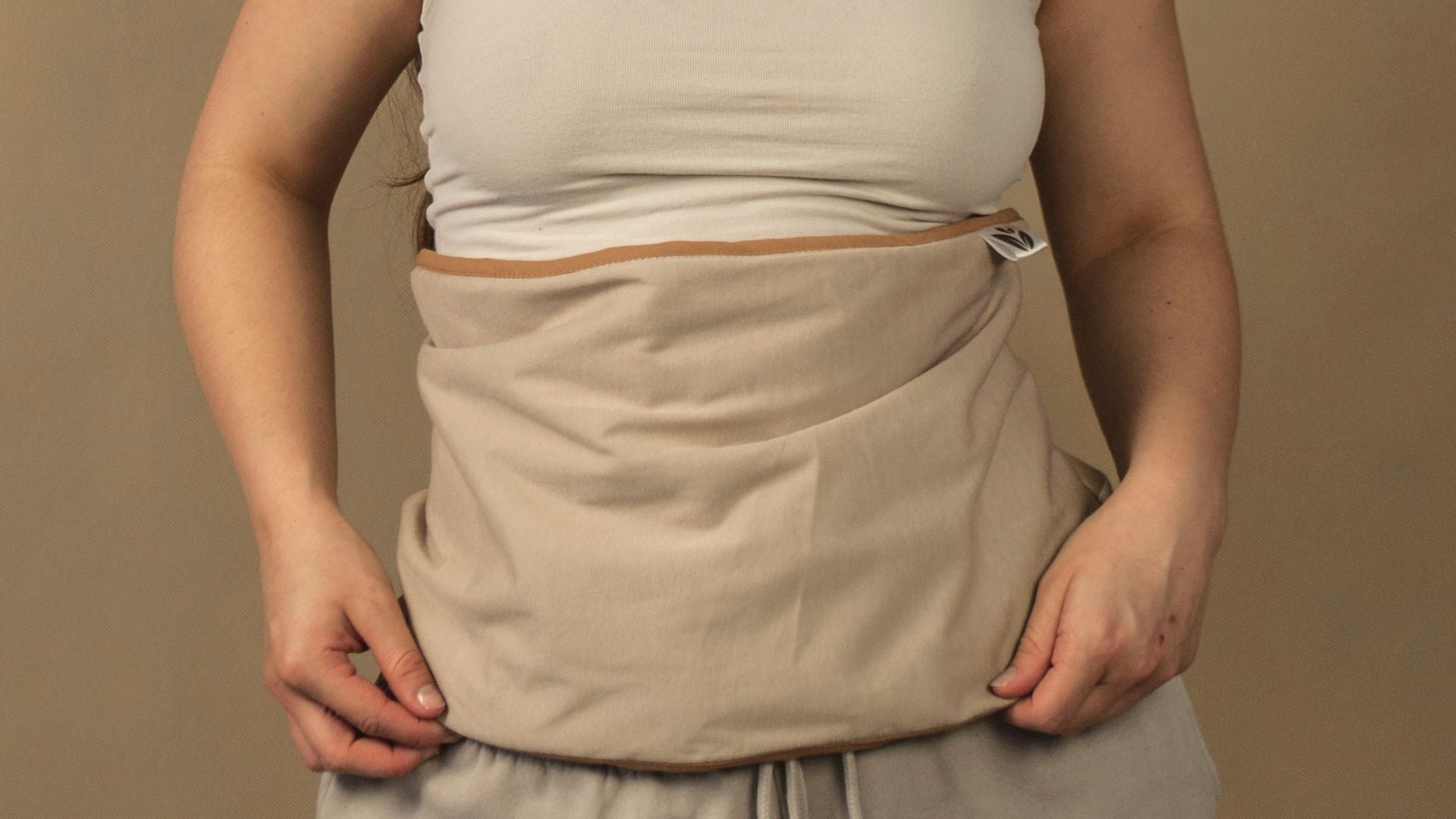 Frau trägt einen beigen Wärmegurt am Bauch.