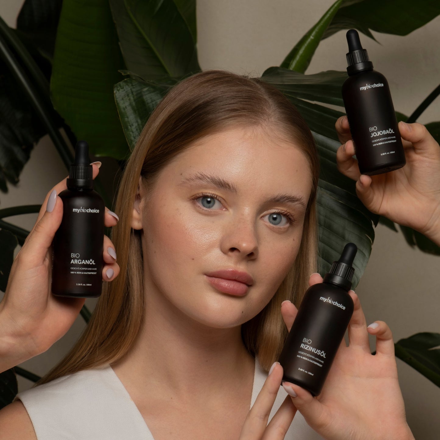 Kobieta prezentująca naturalne bio olejeki mybiochoice – arganowy, jojoba i rycynowy na tle zielonych liści.