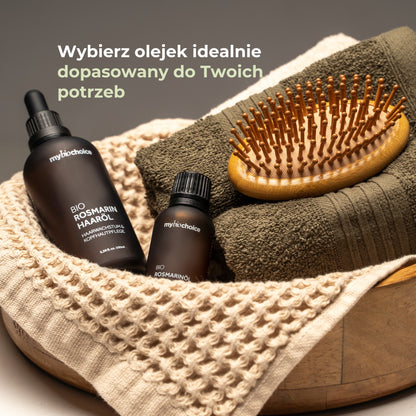 Zestaw olejków rozmarynowych mybiochoice z ręcznikiem i drewnianą szczotką na tle tekstyliów.