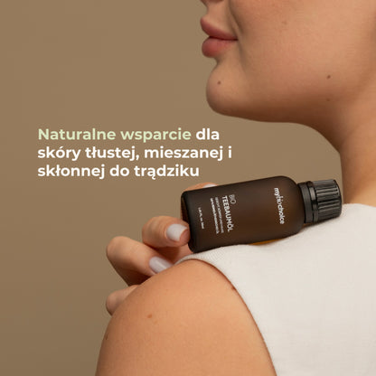 Kobieta z buteleczką olejku z drzewa herbacianego na ramieniu — naturalne wsparcie dla skóry tłustej i trądzikowej