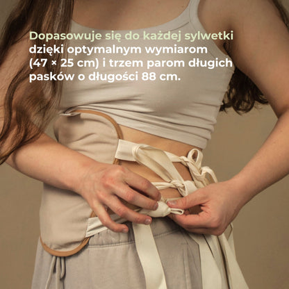 Kobieta wiąże opaskę do okładów z oleju rycynowego, dopasowaną do sylwetki dzięki długim paskom.